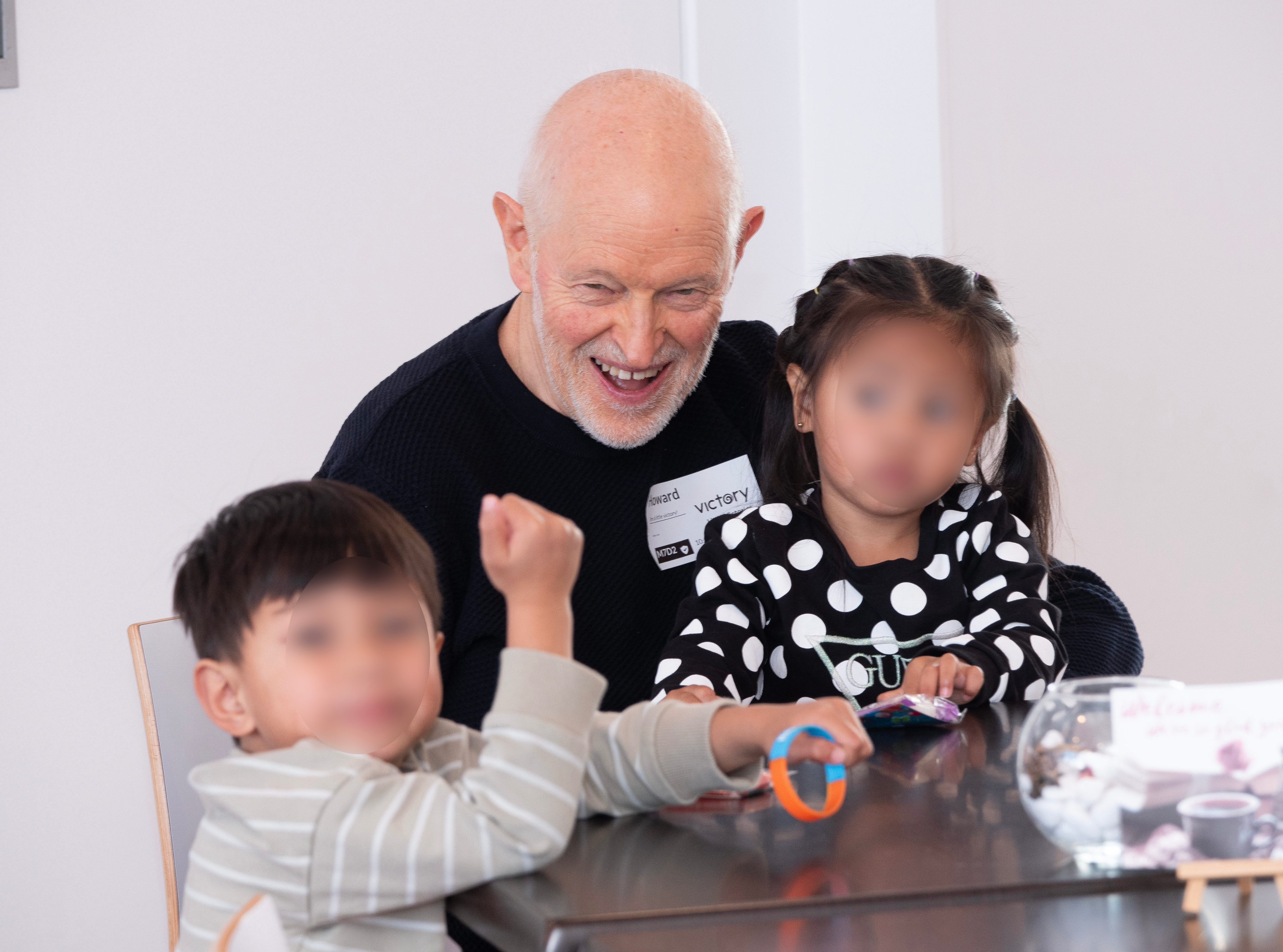 Smiling grandfather with kids on lap.